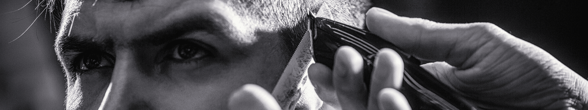 Coiffeur qui fait un dégradé avec une tondeuse à son client